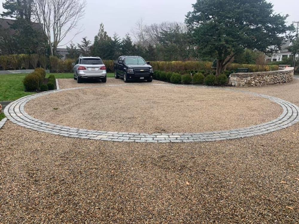 Gravel parking area featuring two cars and a circular stone design.