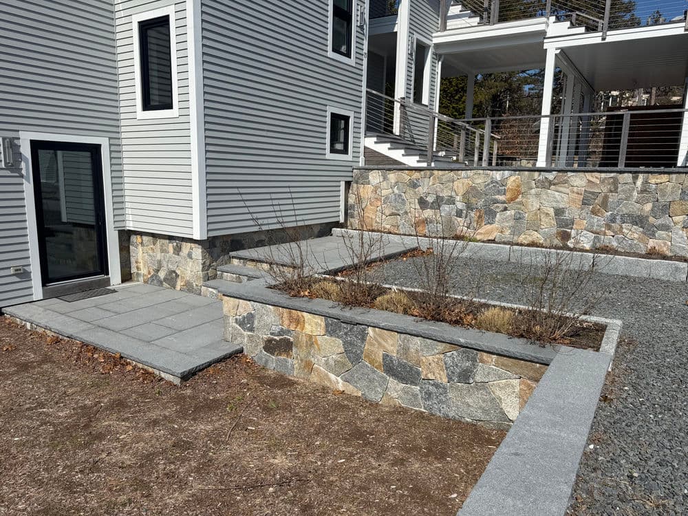 Modern home exterior with stone landscaping and a gray stone patio.